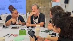 People sitting around a stable, discussing and listening.