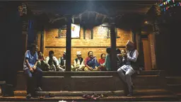 Group of people gathered in a outside sitting spot in the evening, talking and laughing.