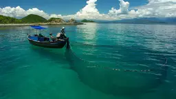 Team of small-scale fish farmers in a boat, casting a net in the water.