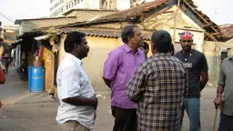 Group of men standing and talking in front of a building.