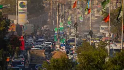 Aerial photo of a busy street, packed with vehicles through a smoky haze and with flags flying above.