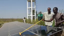 Two farmers washing up a solar panel in Senegal.