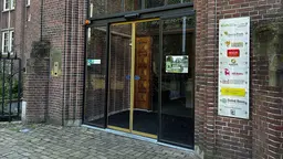 The front glass doors to an office building, with a name plate of business owners beside it on the wall.