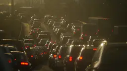 A queue of cars seen through a foggy pollution haze.