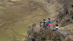 An aerial photo of a group of people in the distance, standing on hillside outcrop and overlooking a valley.