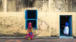 A woman wearing colorful clothing walking into a building.