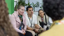 People from the Youth Group at COP30 gathered and listening to someone speak off-camera.