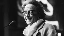 A woman smiles as she stands in front of a microphone.
