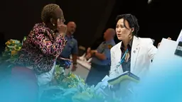 Two people with lanyards hanging from their necks engage in a discussion.
