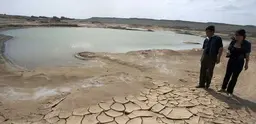 People stand by a drought-stricken lake in Xinjiang Province, north-west China.