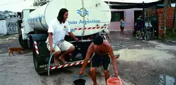 A man carries buckets filled with water from a water tanker in Retiro, a shanty town in Buenos Aires, Argentina.