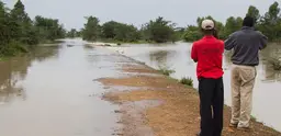 Men survey a flooded road in Kenya. 