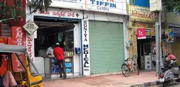 Street scene of small shops and a rickshaw in a city in South India. 