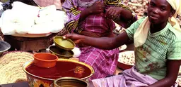 A woman sells palm oil in a market in west Africa.