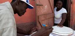 Two community leaders prepare service contracts for a novel container-based sanitation service before installing toilets in users' homes in Cap Haitien, Haiti (Photo: Felipe Jacome)