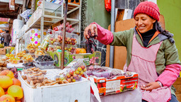 A stallholder measures her produce in a marketplace