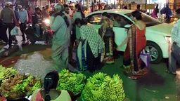 A street scene with pedestrians, stallholders, motorbikes and cars 