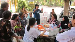 People gather around a table at an outdoor meeting