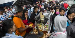 A food vendor is surrounded by people in a busy street