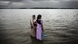 Two women look out over the rising sea water
