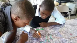 Two men huddle over a map and make annotations.