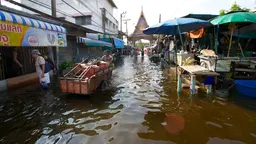 A trader wades through knee-high flooded water in a marketplace