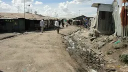An open sewer runs in front of homes