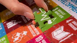 Someone puts the final piece of a jigsaw into the puzzle