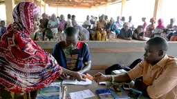 A woman showing her identification card to two officials