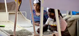 Two women sit as they hand pick coffee beans at a desk