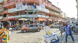 View of a building on a street corner, with people crossing the road in the foreground