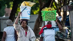 Two people carrying containers on their heads