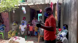 A man in a face mask talking to a group of people
