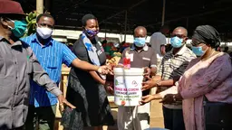 A group of people pointing to a bucket