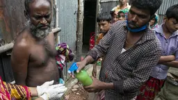 A man sprays disinfectant onto a person's hands