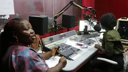 Two woman sit at a radio production desk