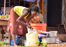 Woman washing dishes with a jerrycan.