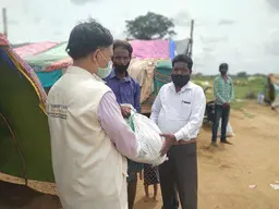 Man handing a package to another man. They are all wearing face masks.