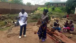 A man writing notes while a woman watches.