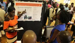 Woman in workshop points at a poster. Audience looks at her.