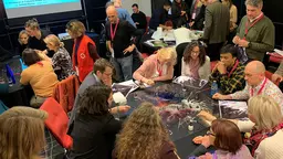 Groups of people gather around tables and talk