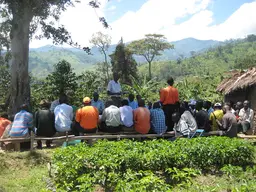 Community group siting in a circle and listening to a speaker 