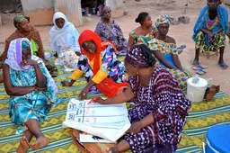 A group of women writing notes on a poster.