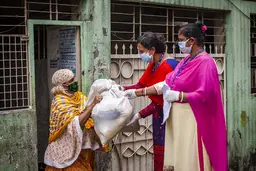 Women delivering a package to another woman, all wearing face masks.