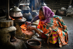 Woman cooks using wood fire