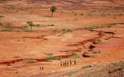 Aerial view of an arid landscape. A group of people walk.