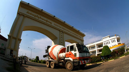 A concerete mixing lorry drives under an arch that has the words 'Phnom Penh Special Economic Zone' written on it