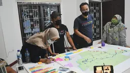 A group of people stand around a map on a table.