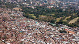 An aerial view of Nairobi, with slums in the foreground alongside green space 