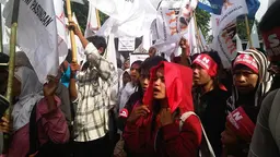 A crowd of women and men hold banners and shout in protest